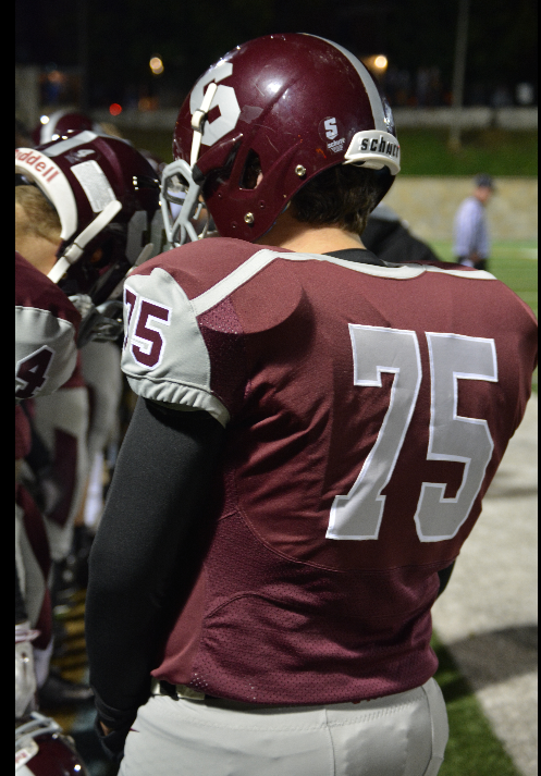 Photo by Isabella Anderson 

Senior Colin Corbett (75) stands on the sidelines of a State High football game.