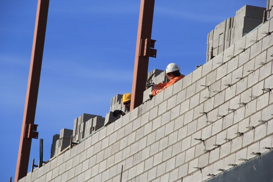 Workers place bricks on one of the walls. 