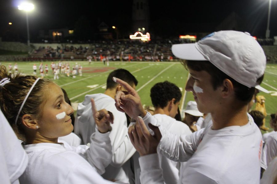 Senior Patrick McNutt (right) and  junior Sarah Finton (Left) put face paint on each other during the Varsity football game. “The environment of the student section is full of enthusiasm and support from our school, and it’s a great way to bring people of all grades together,” Finton said.  
