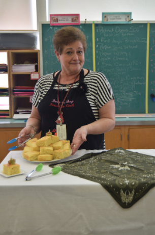 Mrs. Judy in her classroom in the State High North building displaying a side dish prepared for a class cooking lab. 