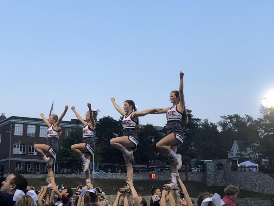 Four varsity cheerleaders, flyers on the team, are lifted into the air during one of their cheer routines at the 2018 State High Homecoming football game. Rylie Grube, varsity cheerleader, said, “ I love football season and getting the chance to watch the game on the field with my team.” 
