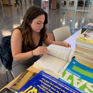 Allaina Wagner, senior, studies for her SAT subject test while helping to sell practice booklets. Wagner is starting her studying early to best prepare herself for her subject tests. “It has been a very busy year for me so far…I took a diagnostic test and did very poorly on it so [I am] kinda nervous,” Wagner said.