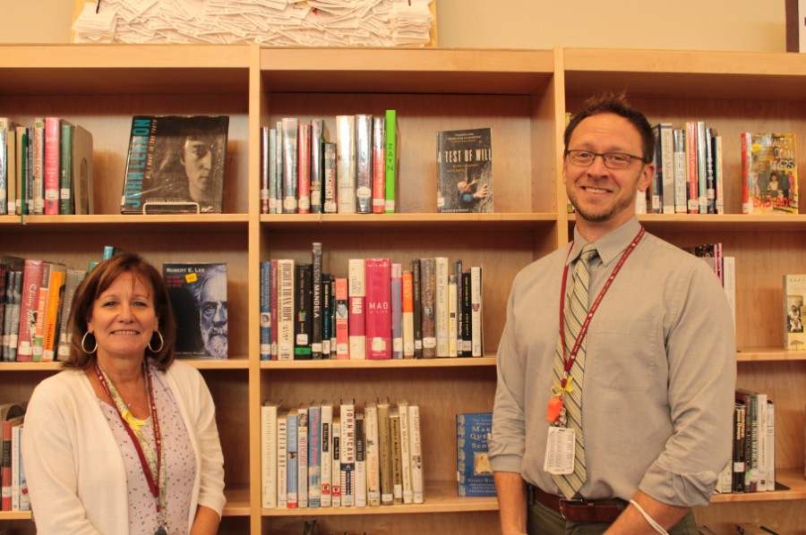 Librarians+Dr.+Fuhrman+and+Mr.+Morath+stand+smiling+in+front+of+one+of+the+numerous+shelves+of+books.+Photo+by+Lacey+Sheaffer.%0A
