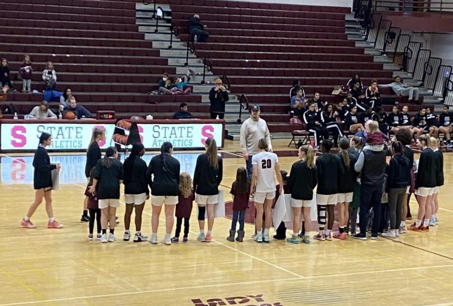 Girls team standing with kids from their old elementary and middle schools in honor of kindergarten night. 