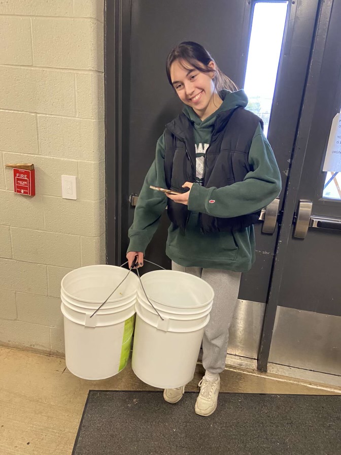 Environmental Club member Lyla Higgins holding compost buckets. Composting is a great way to reduce food waste and give back to the environment. 