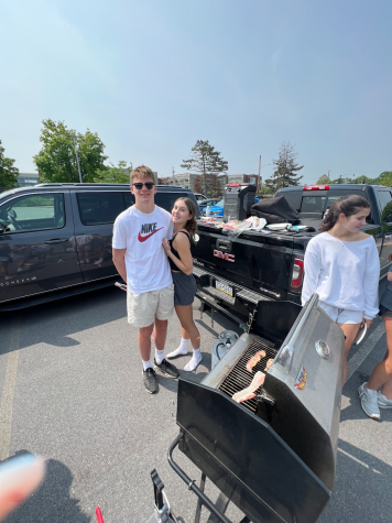Senior Grace Carey and her boyfriend, Tommy Egerer, posing with a grill before school in the parking lot. 