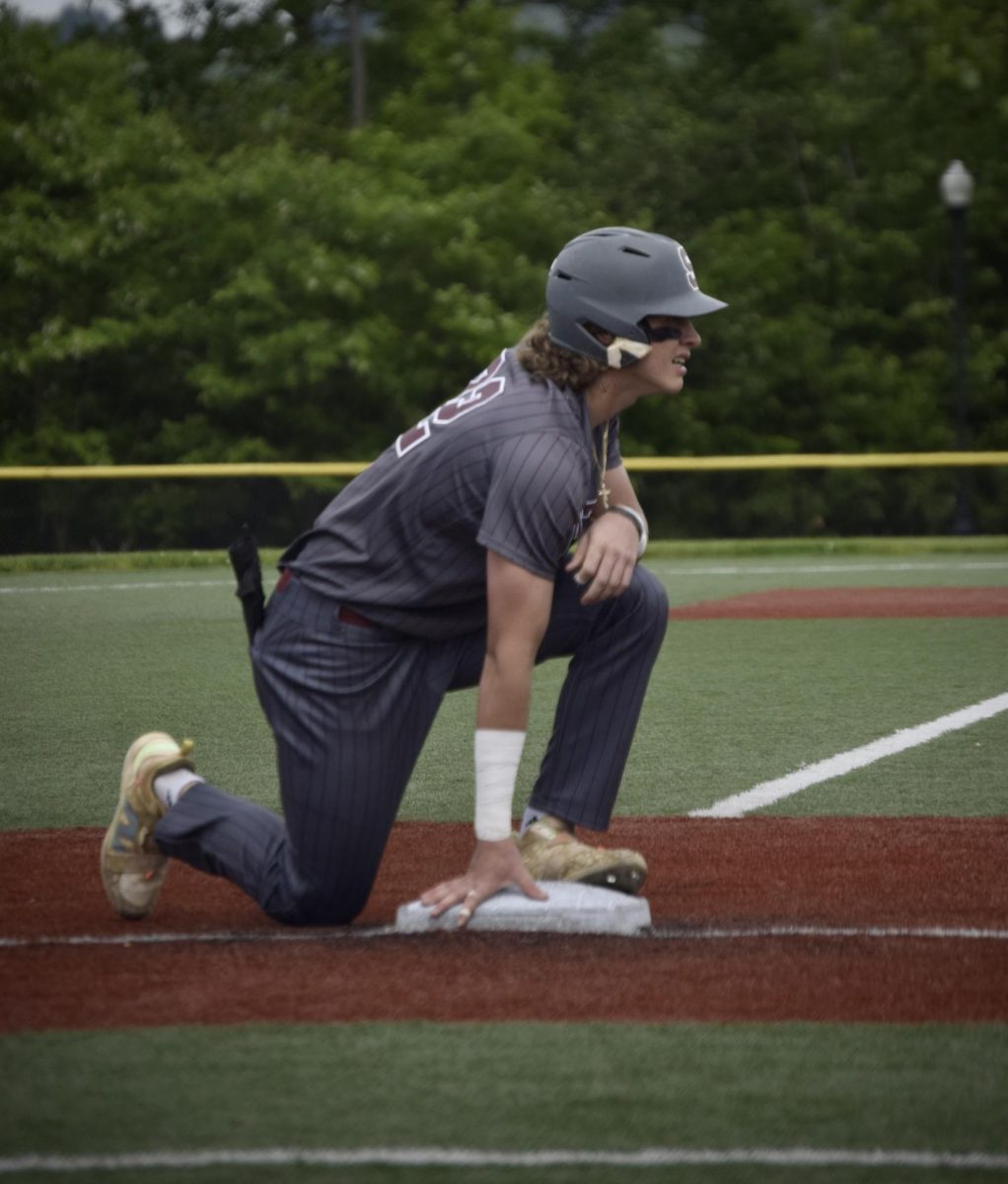Junior Sebastian Rhoades climbs to one knee after sliding into third base in the first inning.