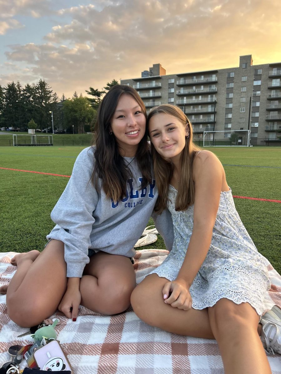 Seniors Inhye Sung and Milli Mortensen hug in front of the sunrise.