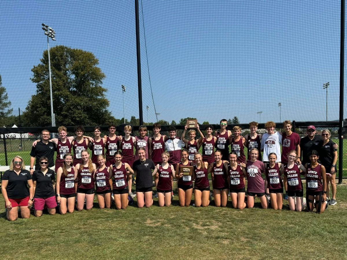 State High Cross Country poses for a photo at Spiked Shoe Invitational. The boys' team is standing in the back row and the girls' team is kneeling in the front row. 2 runners are holding up trophies the team won at the race.