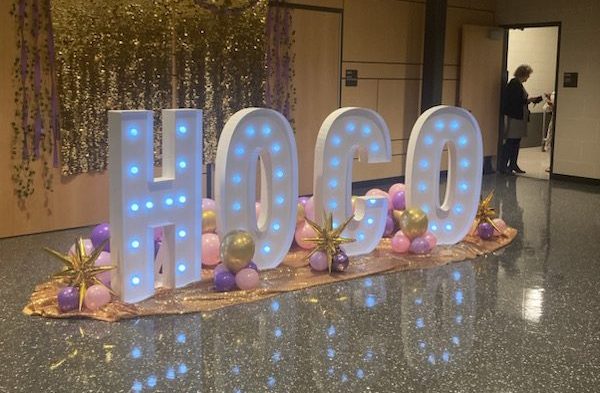 Student Fiona Knowles takes a picture of the 2024 Homecoming photo backdrop with white letters spelling out "HOCO". Photo courtesy of Fiona Knowles