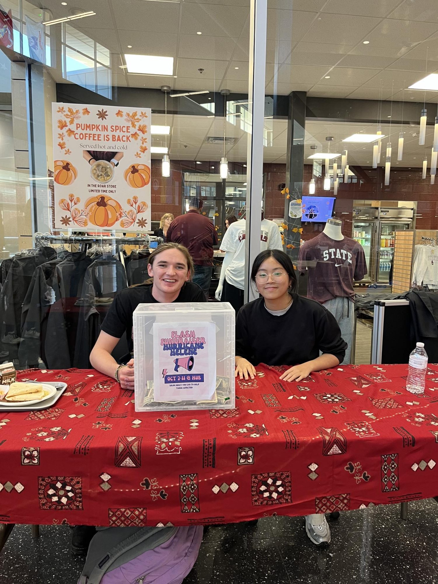 Student Government President Luca Snyder and Treasurer Grace Yang sit at the Hurricane Helene flash fundraiser table in front of the Roar Store during lunch.