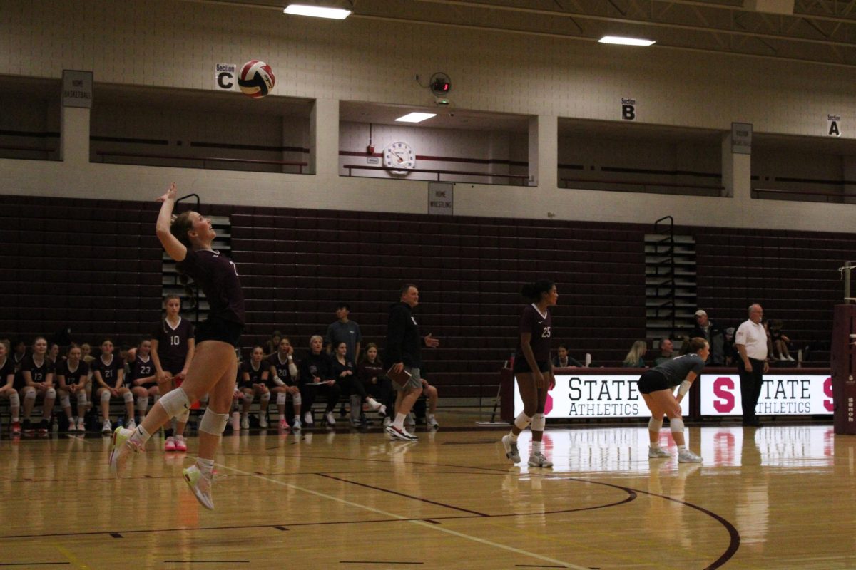 Senior setter Emma Lally (2) serves the first ball of the first set against Cumberland Valley, on Sept. 25. Lally was able to score the first point of the match for the team, opening the first set with cheers from her team and the crowd. She is jumping, about to hit the ball in the air, wearing a maroon shirt with the number #2