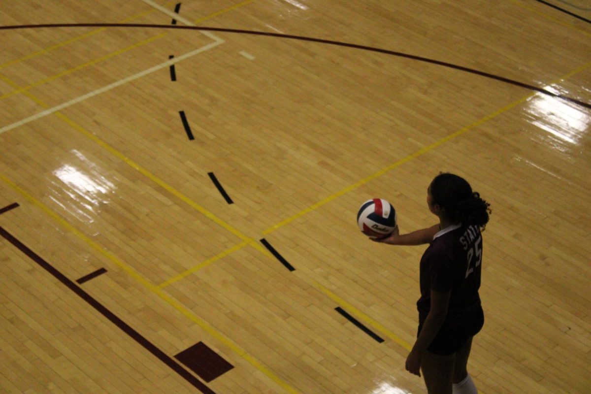 Senior Sarah Tate (25) prepares to serve in the late second set. She is standing, holding the ball with her right hand