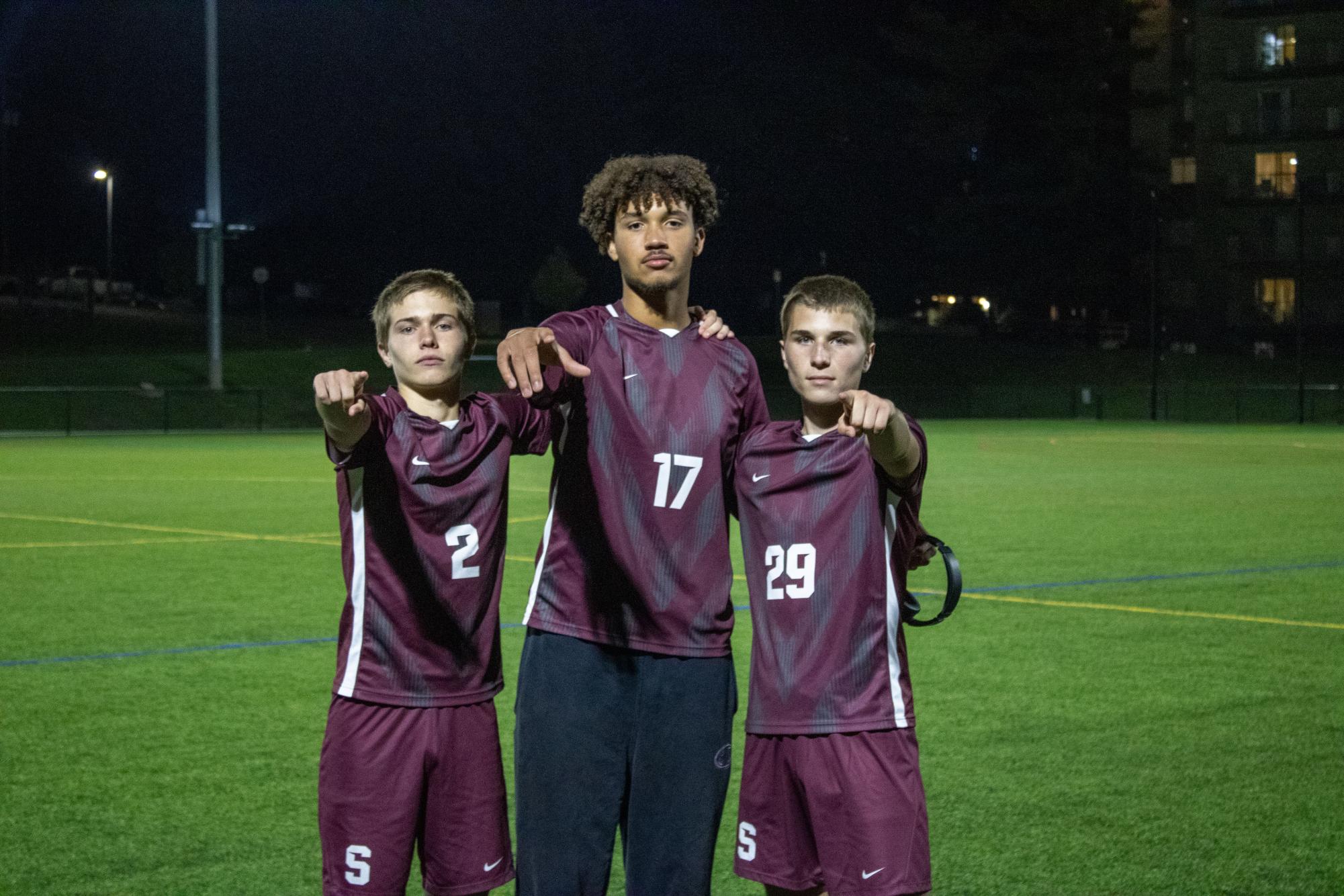 Arthur Cleveland(left), Deondre Sheffey(middle), and Mason Sampsel(right) wearing maroon jerseys point to the camera while on the field after the game.