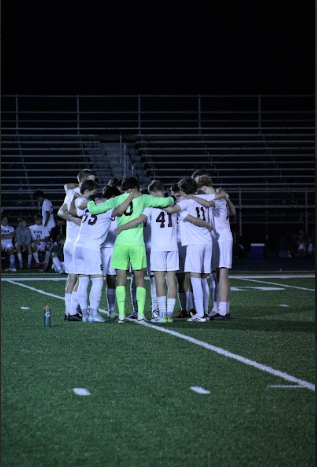 Members of the State High Boys' Soccer Team huddle in a circle on the field, attempting to motivate each other before the overtime period at the District VI championship game on October 23, 2024.