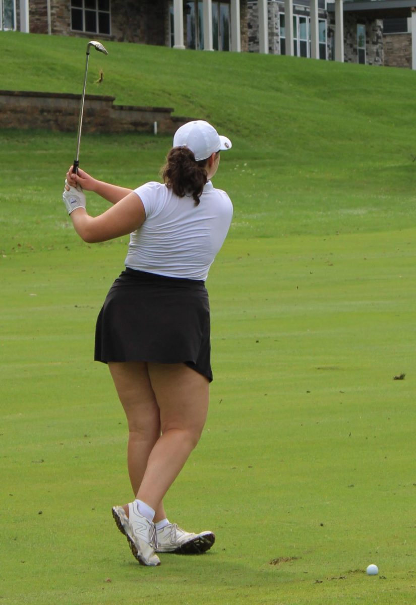 Claire Dworsky turned mid-swing by herself out on a golf field during a game.