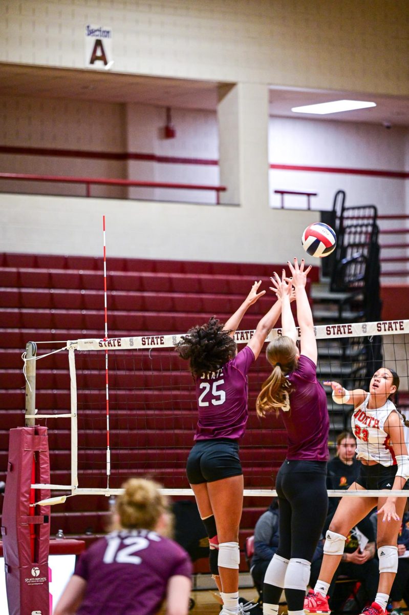 Two SCAHS Girl's volleyball players jump to block an opponents hit.