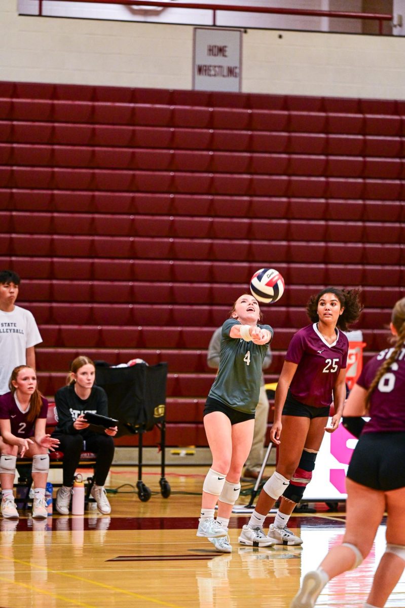 A SCAHS Girl's volleyball player prepares for a dig, her teammates looking on from behind.