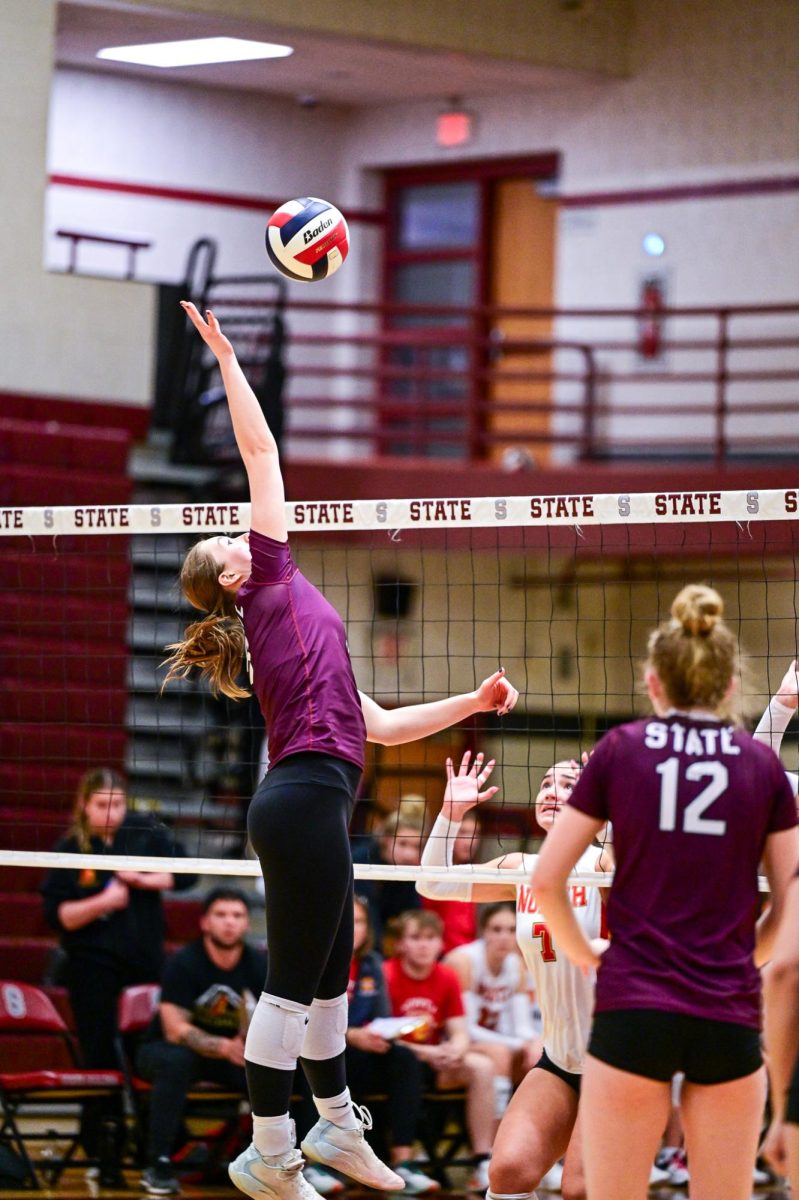 A SCAHS Girls Volleyball player reaches up for a ball as it comes over the net.