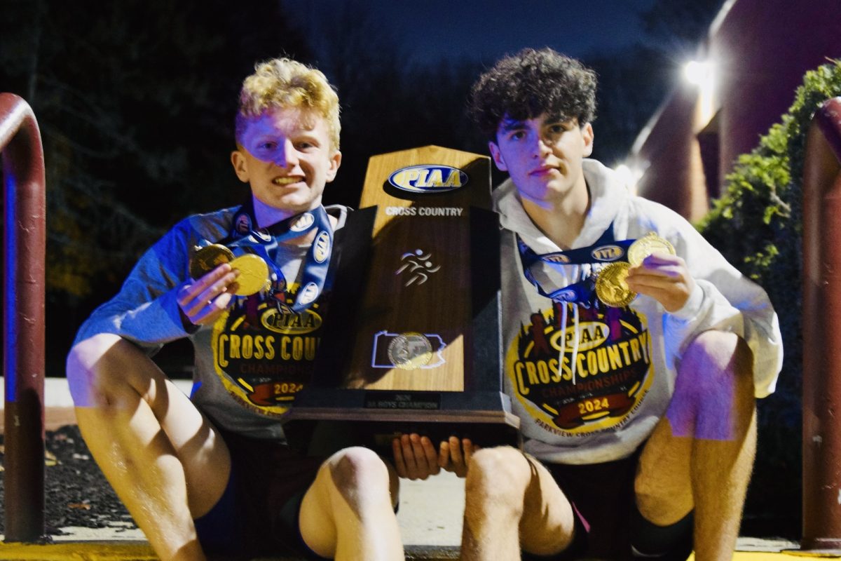 Seniors Owen Coughlin and Isaac Oppermann pose with their medals and the PIAA trophy after the championship race.