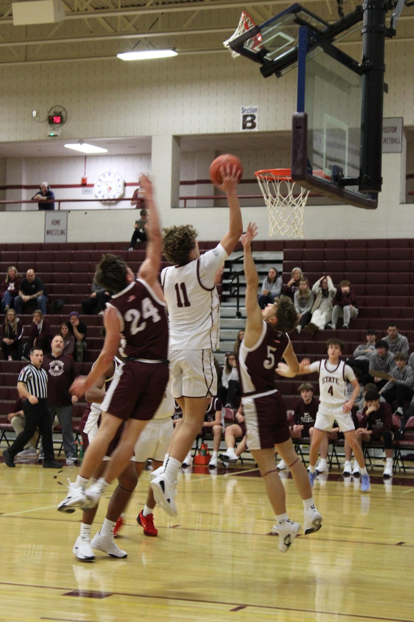 Senior Charlie Yartz hanging mid-air over top of an Altoona defensive player, about to score. Altoona's coach looks annoyed.