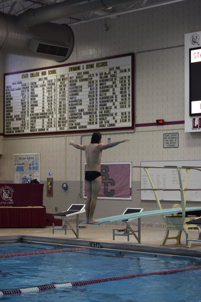 State High Senior, Chris Hill, preparing to execute a back dive during practice on January 10, standing on the board with his back to the water and arms open. Hill has been diving for State High for 4 years, and will continue in college.