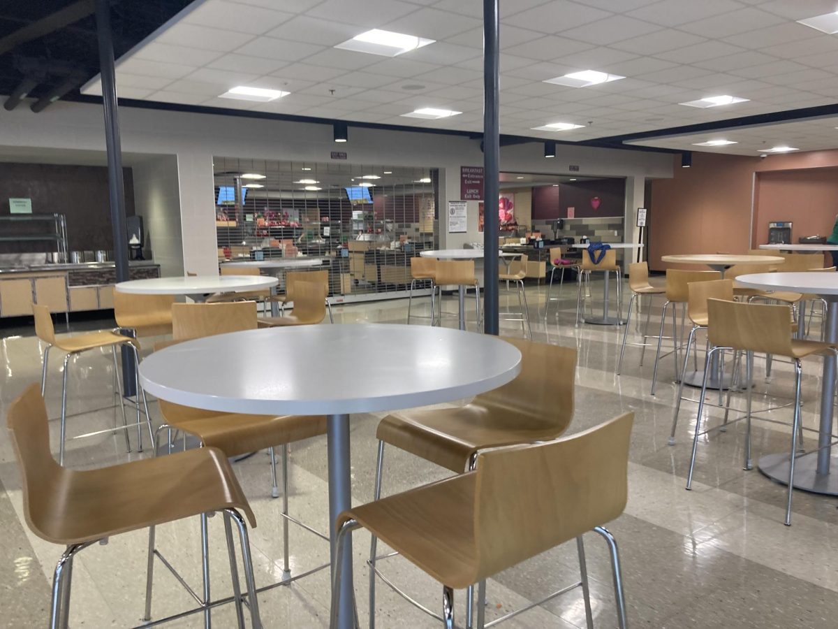 Chairs and tables in the cafeteria are empty following a lunch service at the high school. The food court where kids can get their meals is in the background.