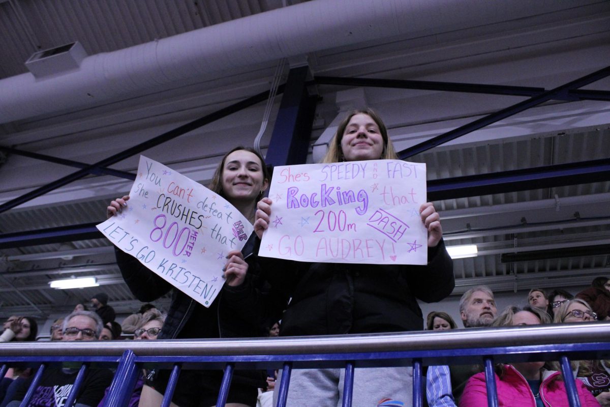 Seniors Claire Heaney and Hayden Kissel showing off the signs they made for their friends, Audrey Thomas, Sophie Baylis and Kristen Schellberg who were participating in the meet. “We want to support our friends during the track meet because we care about them, and they're really good athletes that deserve a sign" Heaney said. 
