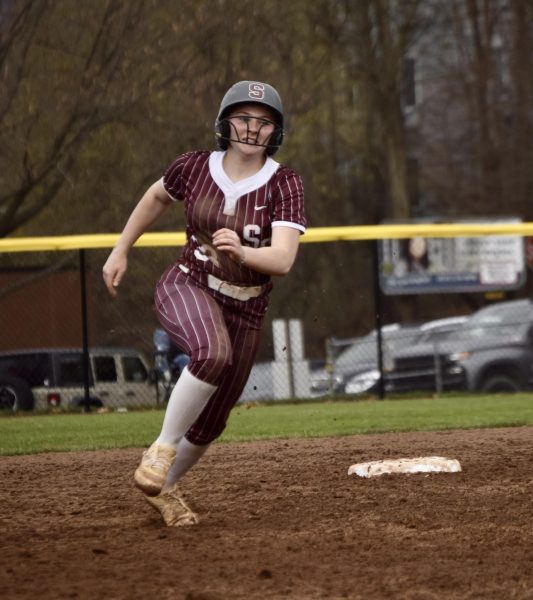 Senior Sydney Wells tears around second base in a maroon uniform with white pinstripes and a gray helmet with a maroon S logo.