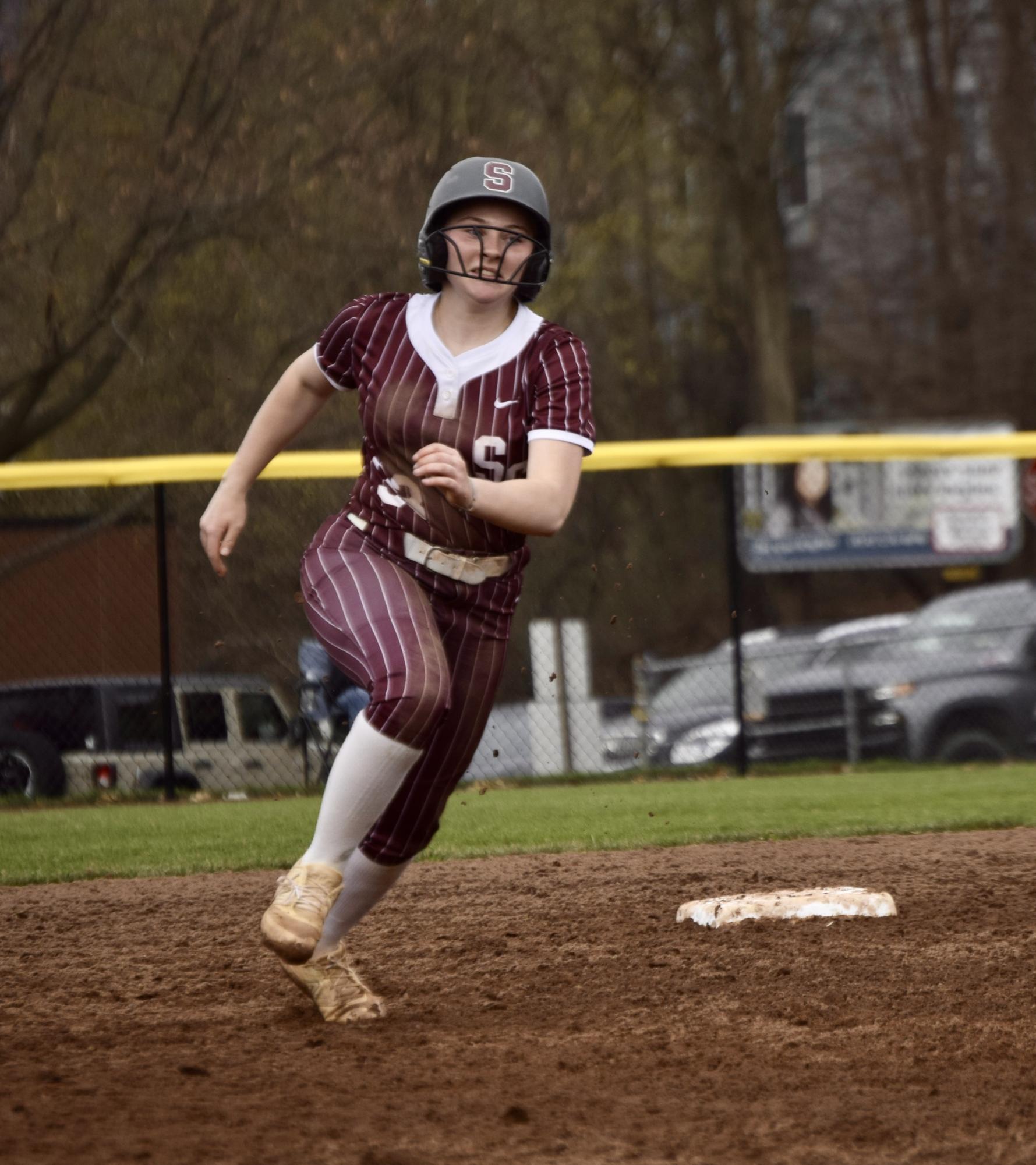 Senior Sydney Wells tears around second base in a maroon uniform with white pinstripes and a gray helmet with a maroon S logo.