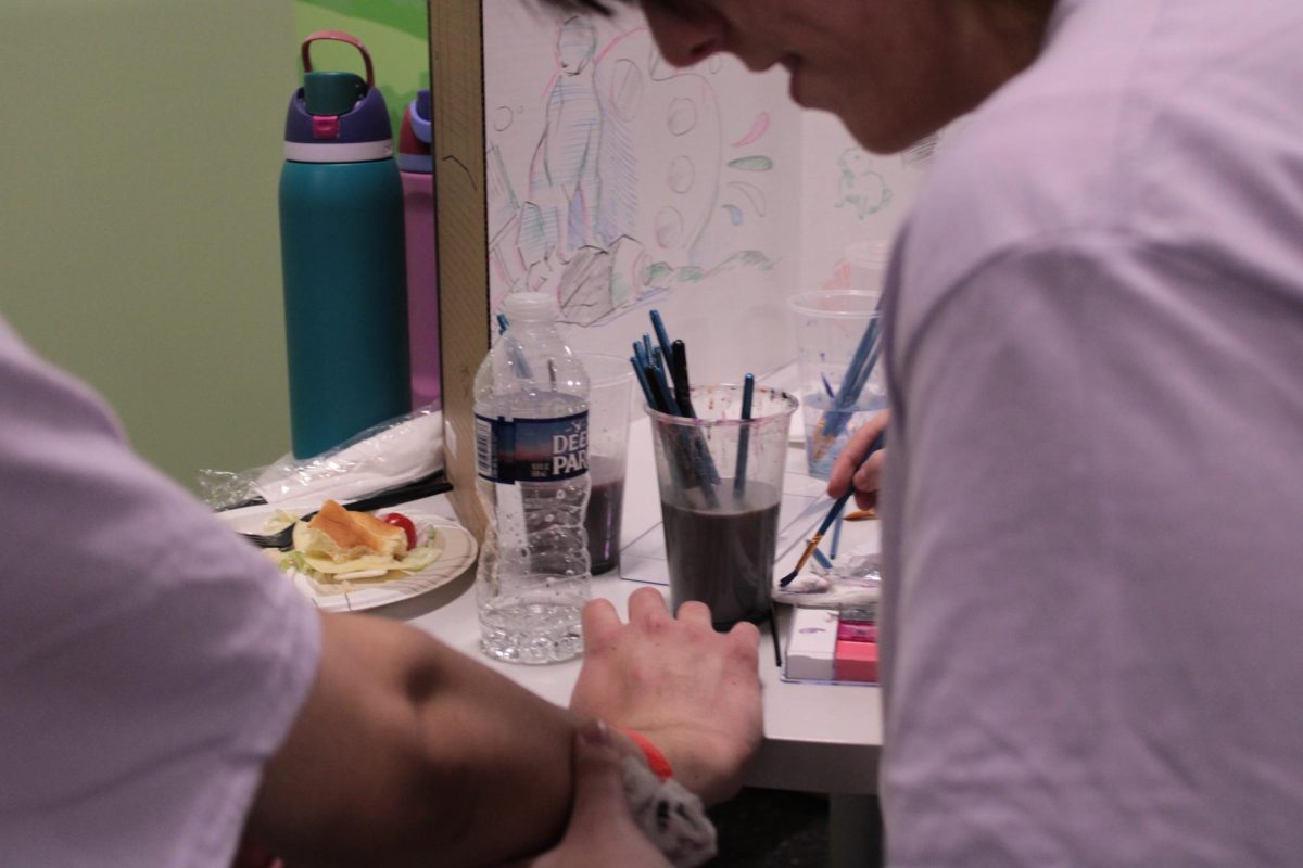 A table featuring body art was provided and run by The Art Club. Junior Charlie Cestone is seen painting on junior Abdullah Ranas' arm. 
