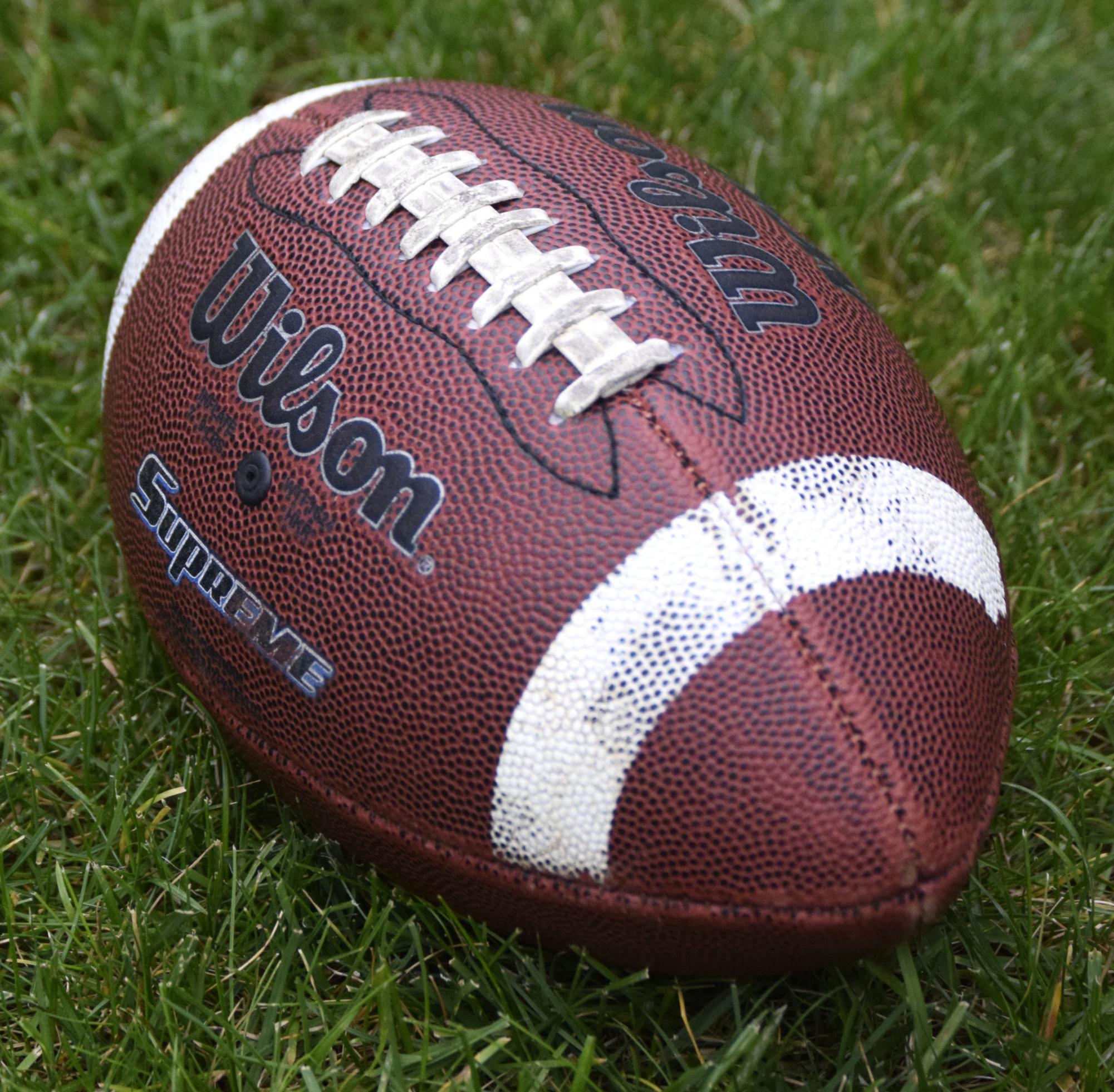 A football lays in the grass on a field.