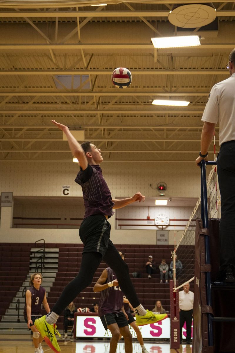 State High’s Carter Weight flys high to spike the ball back at the other team.