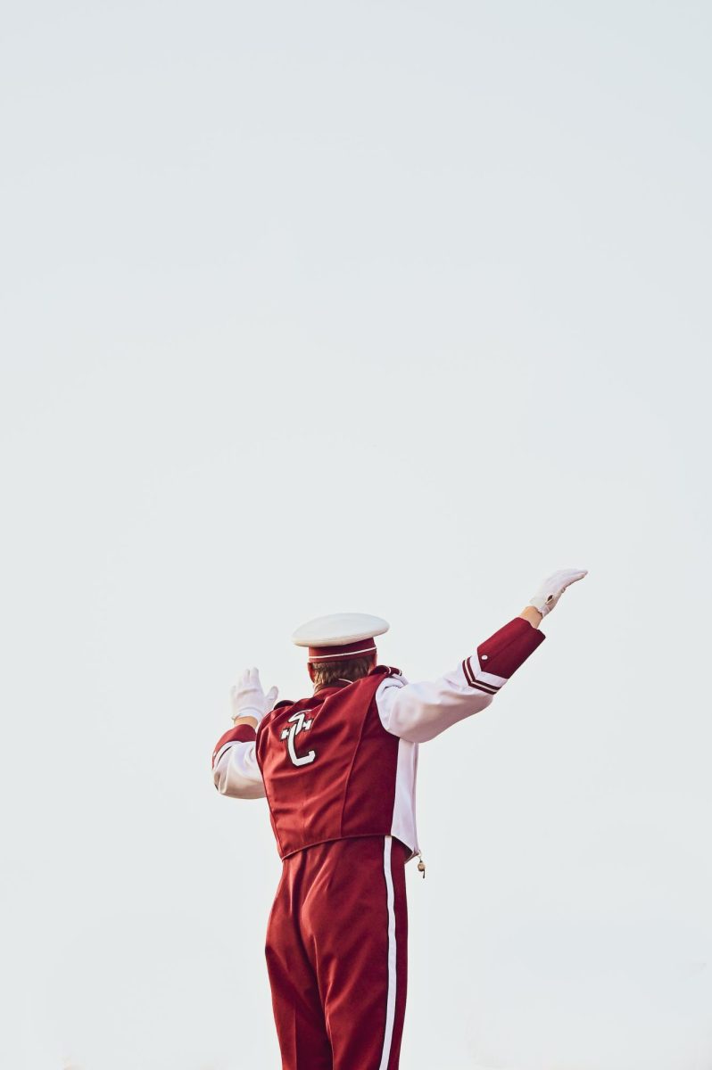 Senior Lewis Gipe, an assistant drum major, conducts the State College Marching Band from his spot in the bleachers. 