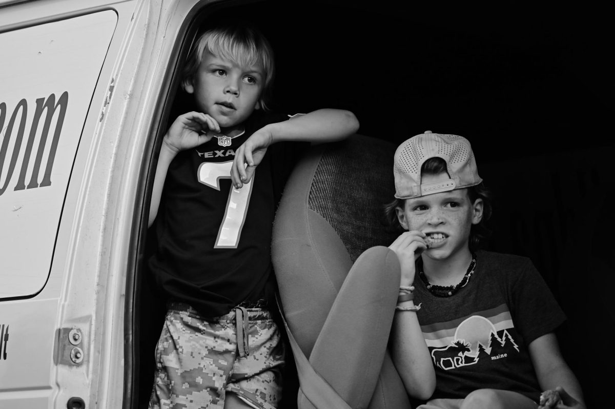 Two boys watch the parade-goers as their van leads the swim and dive float through the streets. 