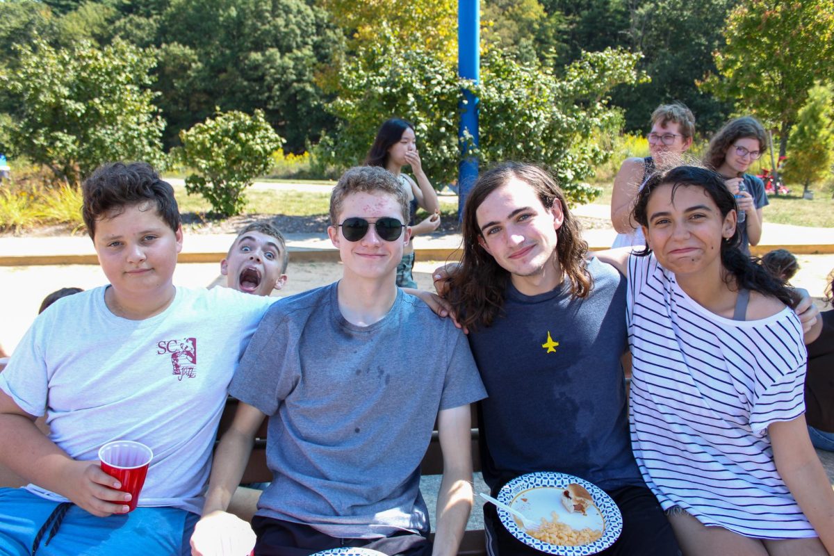 Choir members Jacob Heller, Anthony Shue, Santino DePalma and Emily Richey embrace while enjoying a potluck lunch at the Choir Kickoff with Connor Eliz, Jasmine Lu, Chloe Klinger and Elizabeth Stoner in the background.