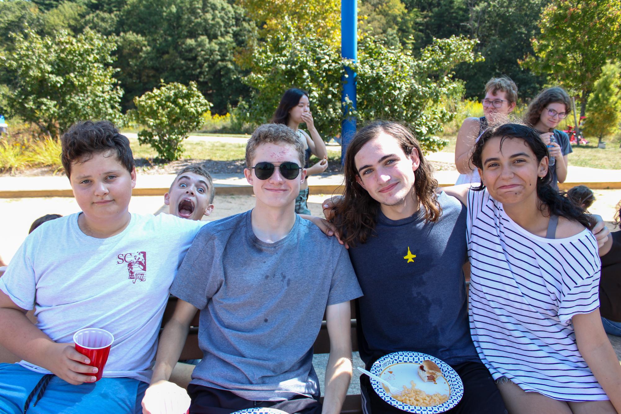 Choir members Jacob Heller, Anthony Shue, Santino DePalma and Emily Richey embrace while enjoying a potluck lunch at the Choir Kickoff with Connor Eliz, Jasmine Lu, Chloe Klinger and Elizabeth Stoner in the background.