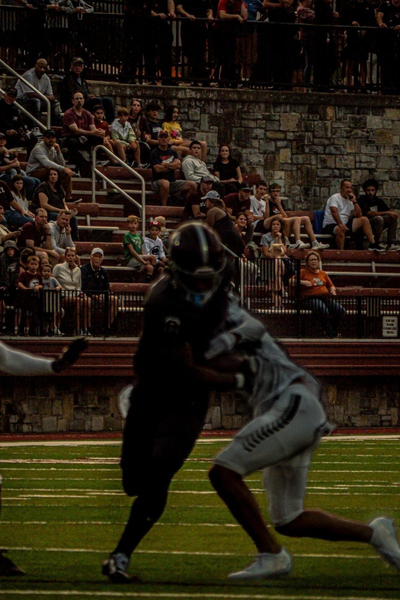 Tae Sheffey, Number 0, breaking a tackle from a Harrisburg player. The photo is focused on the harrisburg crowd i nthe background