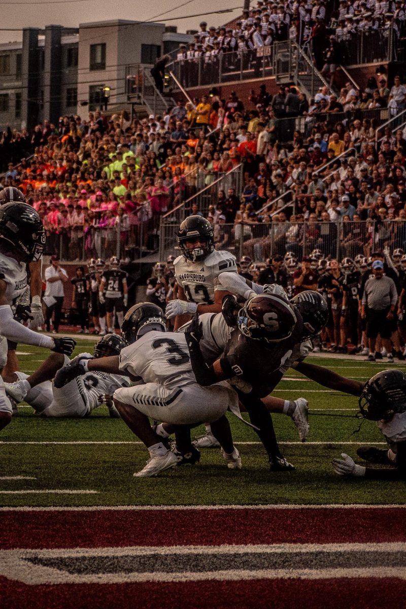 Sheffey lunging toward the goaline, while getting tackled by 3 harriburg player. You can see the color wars student section in the background
