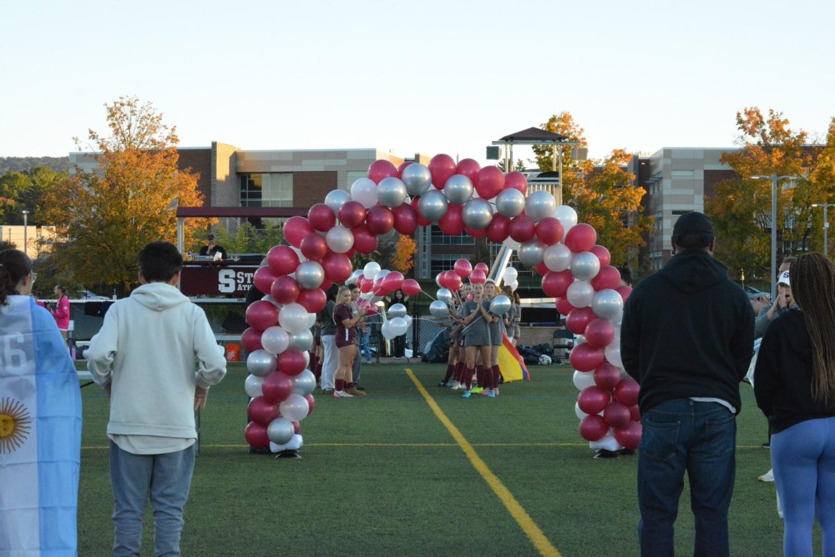Freshman to junior members of the State High girls soccer team form a tunnel for the seniors to walk through on Oct. 14 on the home field. As they walk, their teammates cheer them on and wave their balloons. All the seniors are escorted through the tunnel by a teammate.