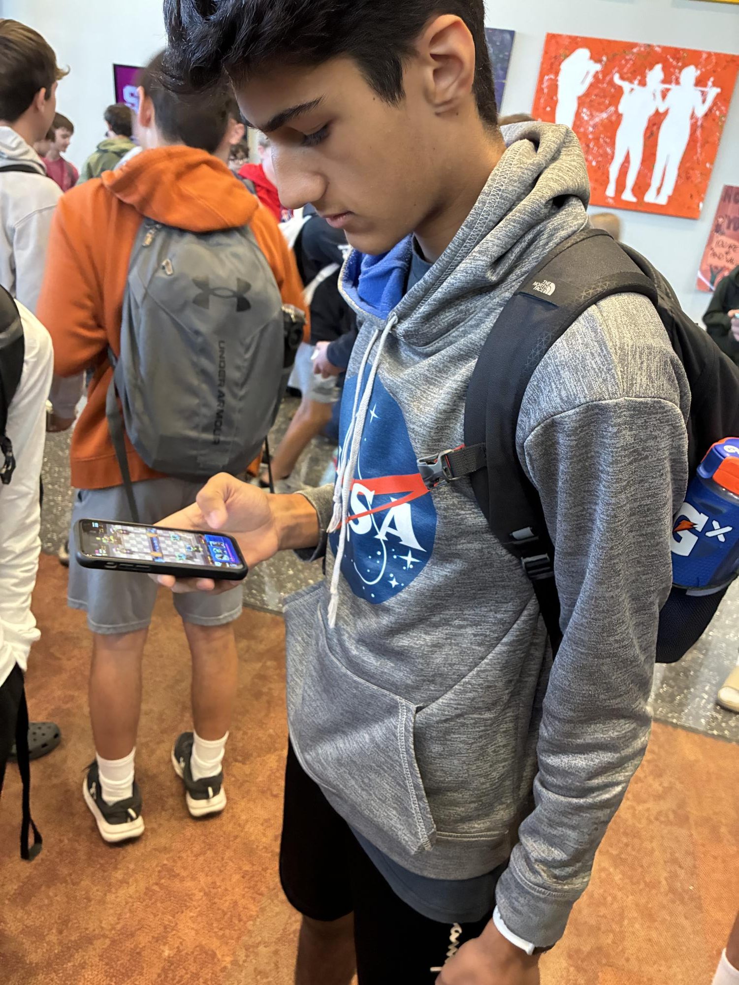 Student uses phone while standing in the Hub before school.