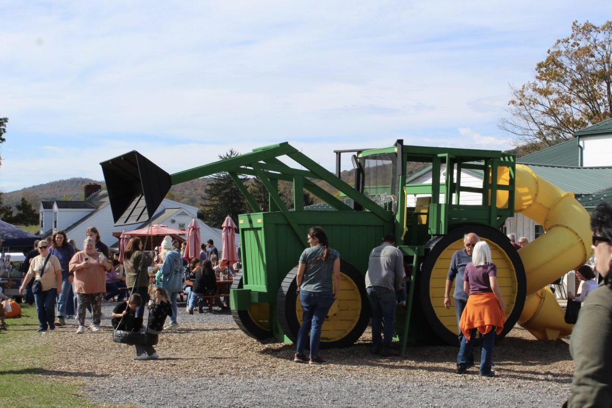 People gathered around and kids playing on the giant tractor play set.