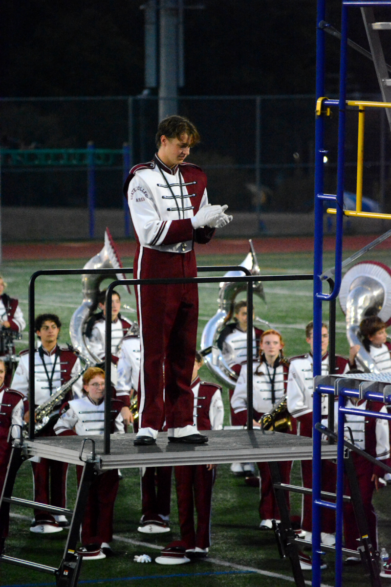 Senior Assistant Drum Major Lewis Gipe takes a break from conducting the marching band at the pep rally. Gipe led the band throughout the parade, walking in front of them and keeping the group in order as many listened to the music.