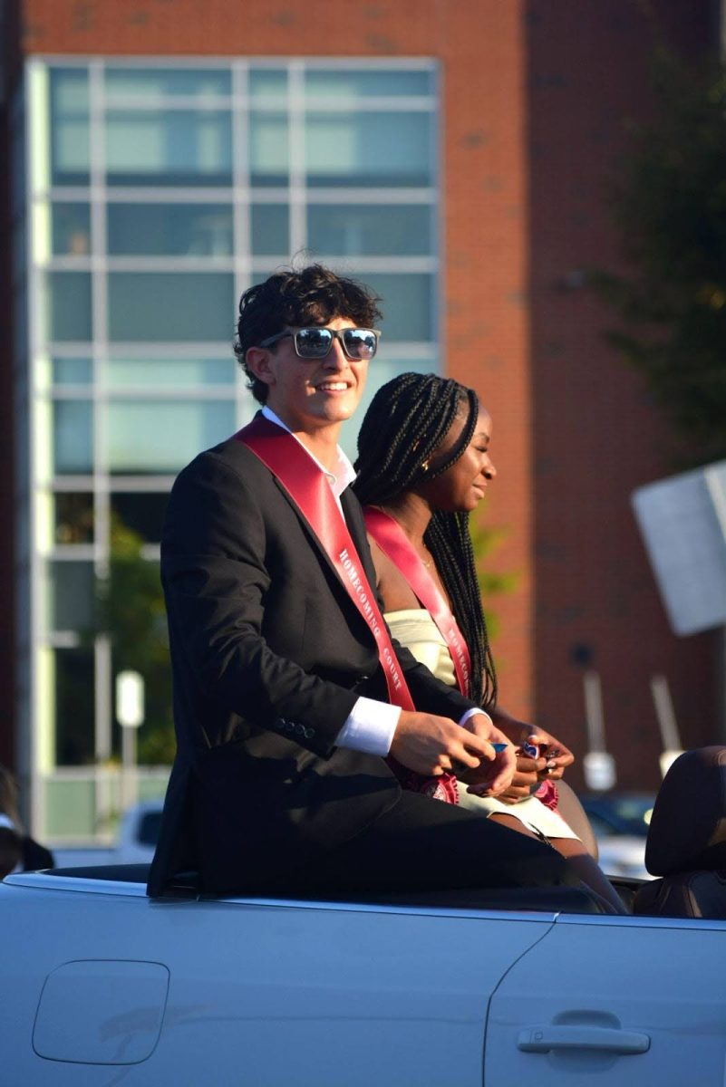 Seniors Max Herncane and Kenna Whitehurst, members of the homecoming court, toss candy to parade-watchers. A day later, the two would be crowned homecoming king and queen at the football game.