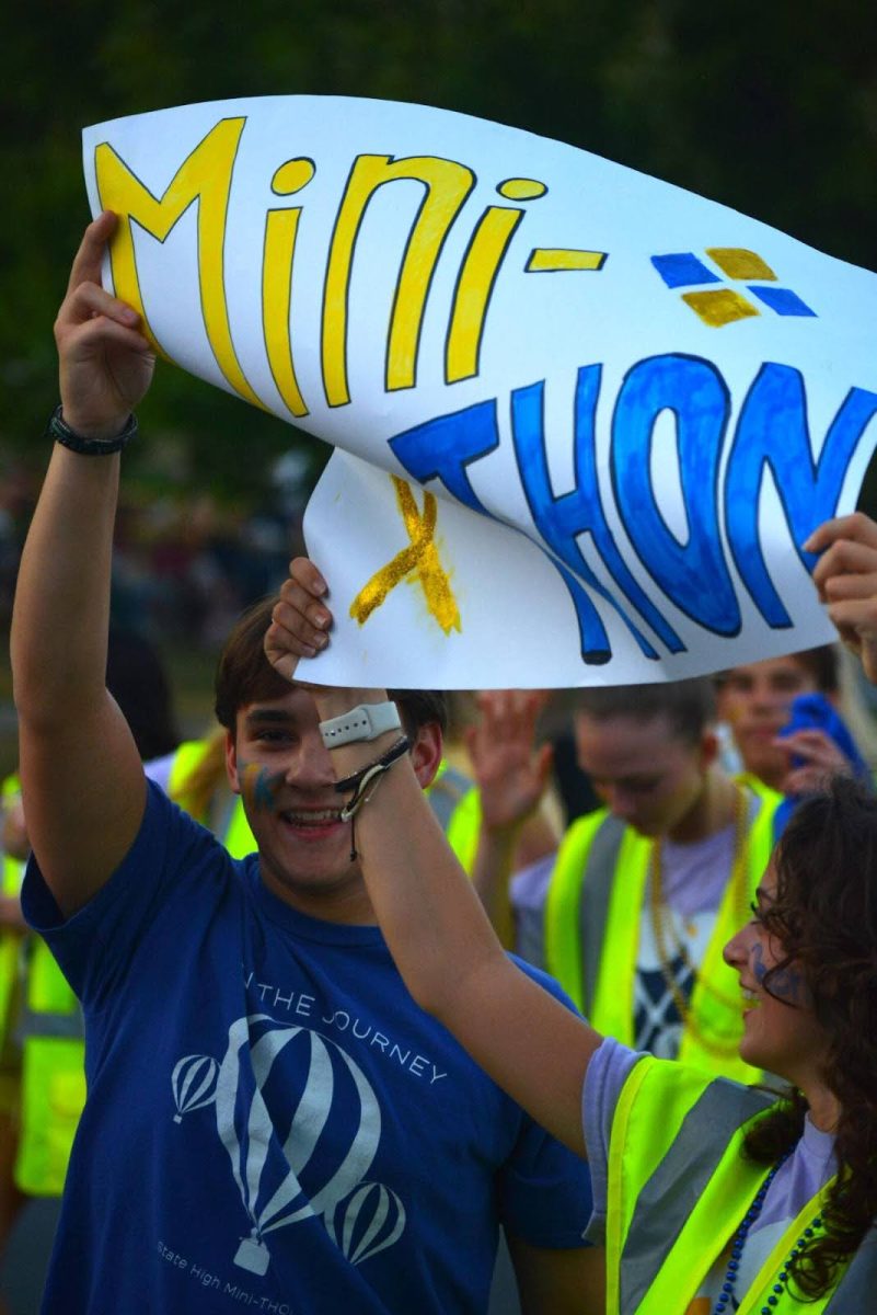 Members of Mini-Thon raise a sign as they walk in the parade. Senior Nathan Gross(left) commented on the atmosphere of the parade. “It was a lot of fun, we put a lot of energy into it…and that was what it was all about; the energy and the vibes of the people on the float,” he said. Senior Mini-Thon Officer Emma Espy echoed the sentiment, “I thought we did well in spreading awareness for our cause,” she said.