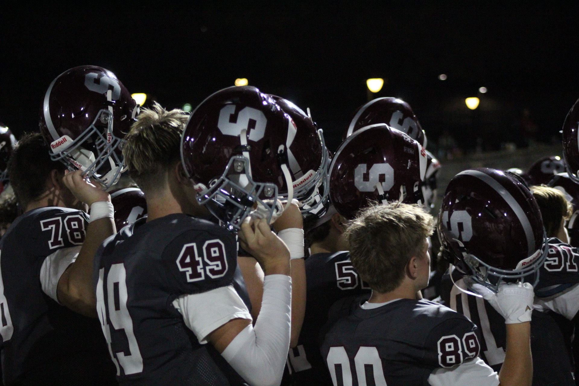 State High Football players raise their helmets while singing the Alma Mater.