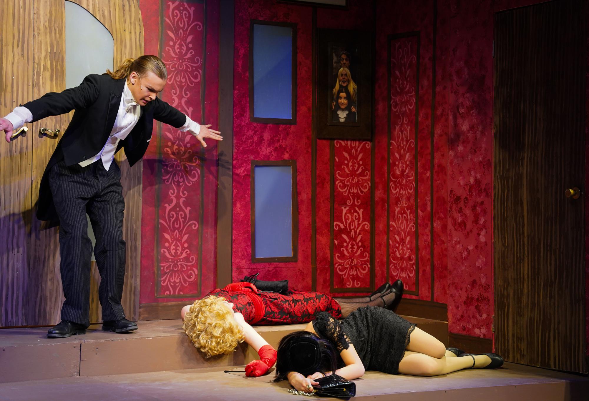 Butler Wadsworth, played by junior Oscar Vebber, stares in shock at the bodies of Miss Scarlett and Mrs. White (Hannah Smith and Anna Christopher)