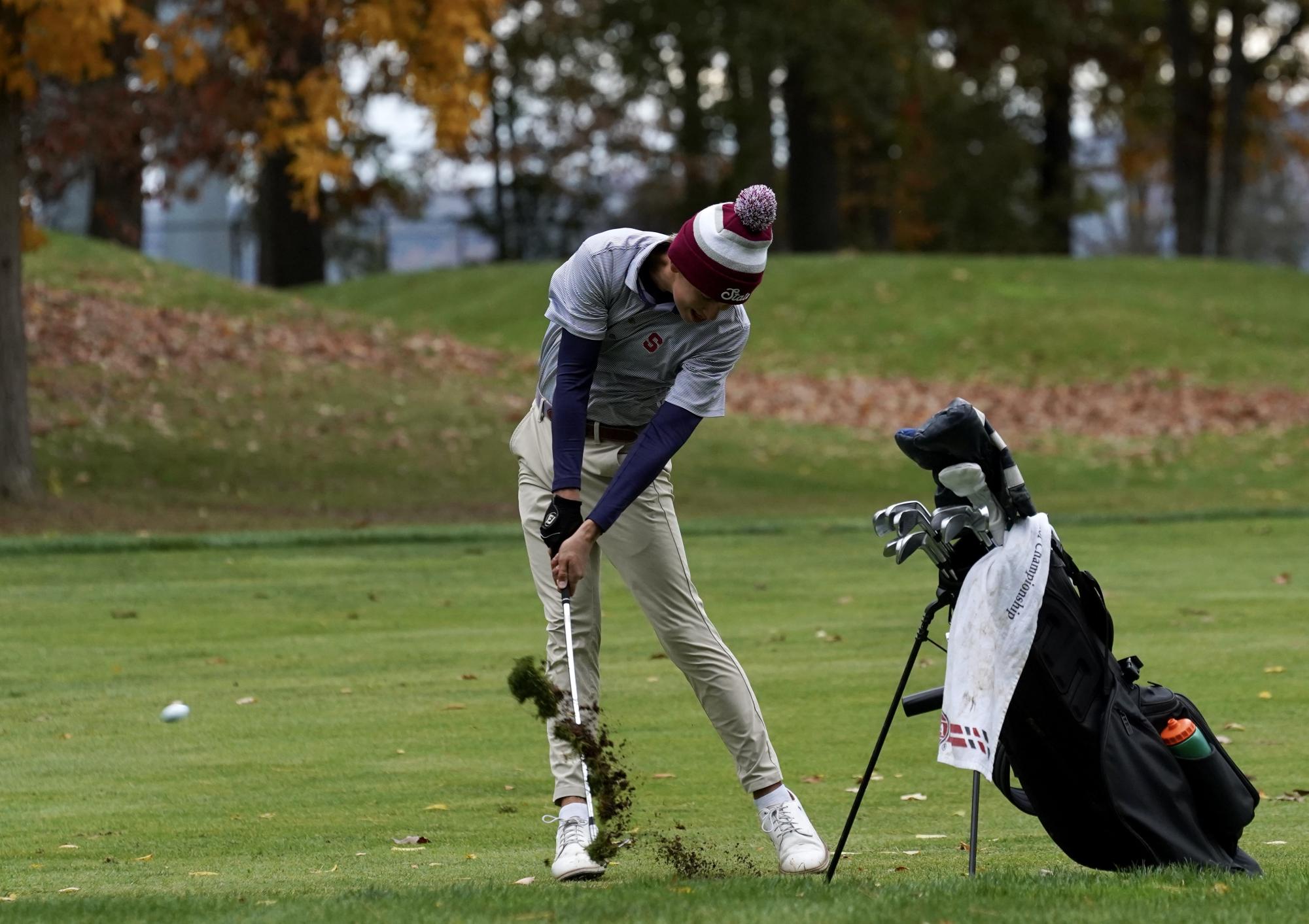 Junior Luke McGraw flushes an iron shot into the seventh green, sending a divot flying through the air.