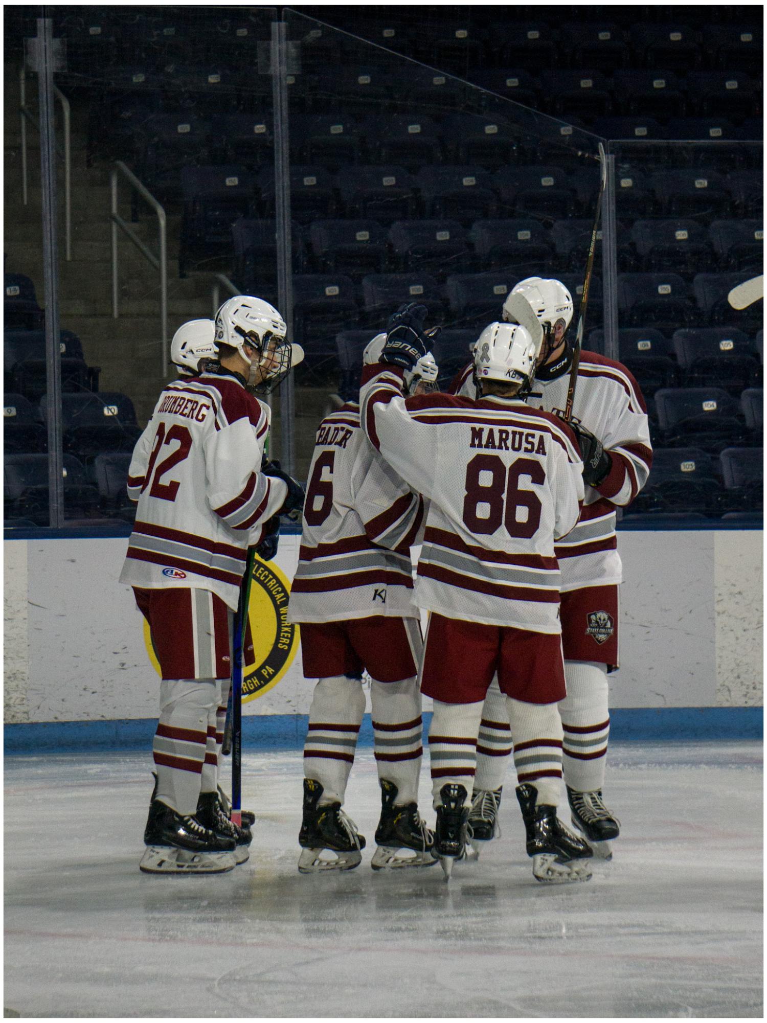 State High Hockey on the ice in a huddle after senior Shane Bader scored celebrating with his teammates.