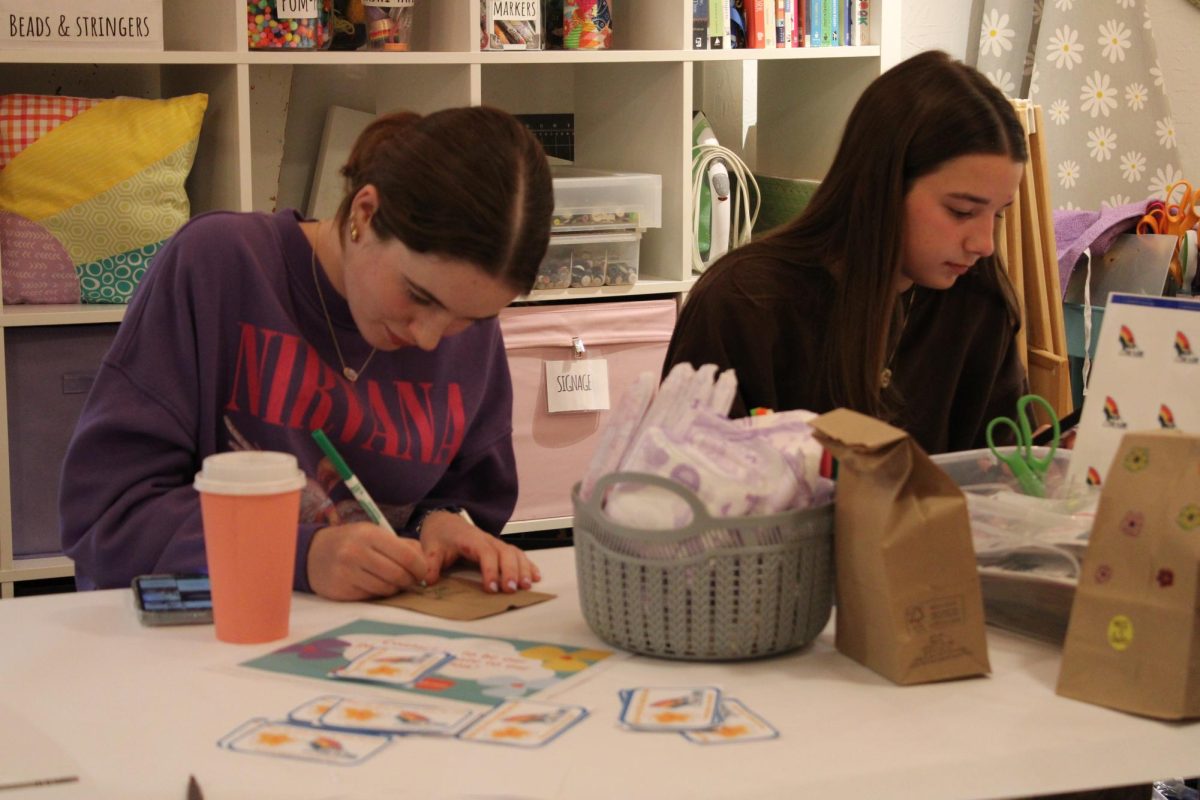 Sophomore Arden Avery and sophomore Geneve Lemay draw on their paper bags during the Go With The Flow packing event on Nov. 4.